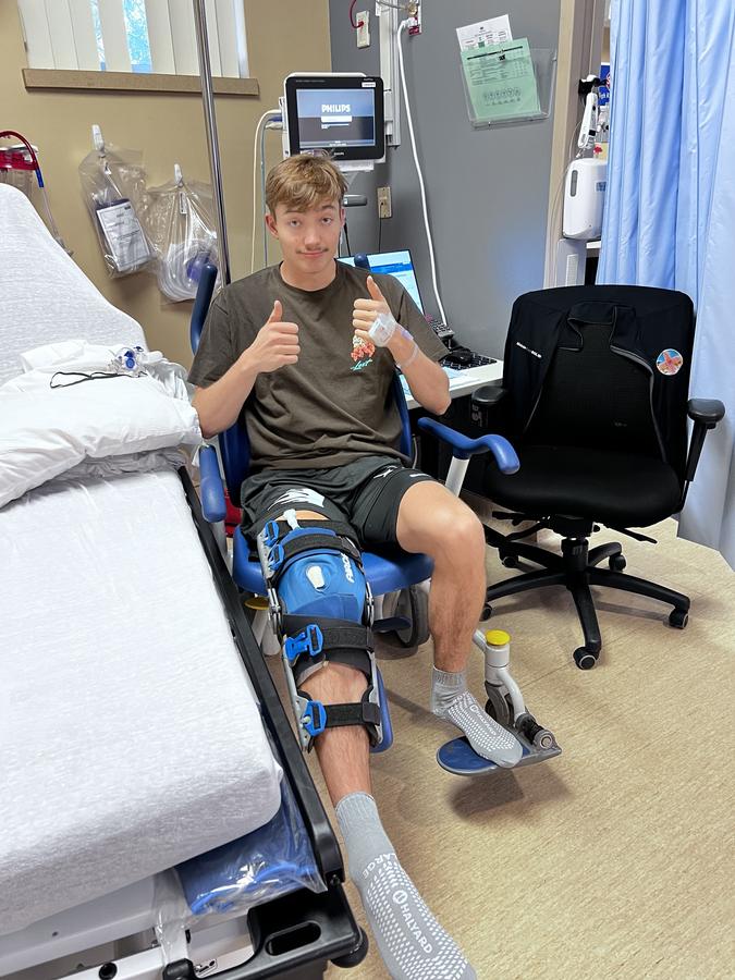 Jake after his first knee surgery, in a hinged knee brace, giving a thumbs up